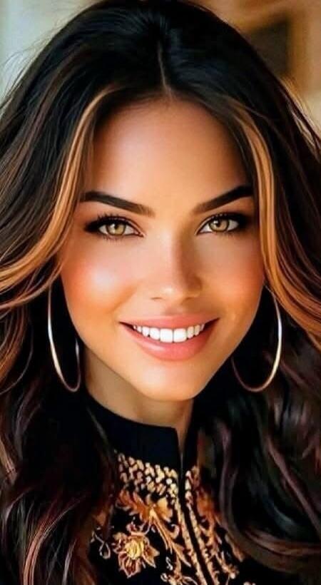 A smiling woman with long dark hair and hoop earrings.