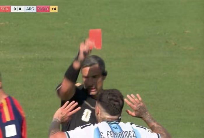 SPA 0 0 ARG 92:29 +4. A referee shows a red card to a football player wearing an Argentina jersey, possibly E. Fernandez.