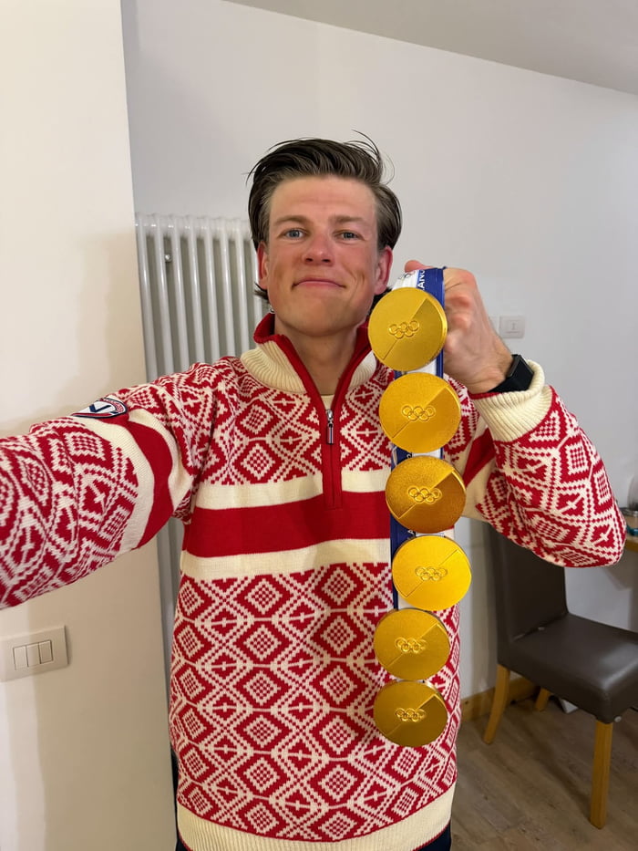 A person holding a vertical string of gold medals, proudly displaying them for the photo.