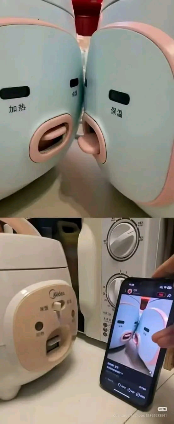 Two small kitchen appliances, possibly rice cookers or warmers, are positioned face-to-face, with their openings resembling mouths sticking out tongues or kissing. Text on the appliances reads 'Heating' and 'Keeping Warm'. A person is recording this scene on a smartphone.