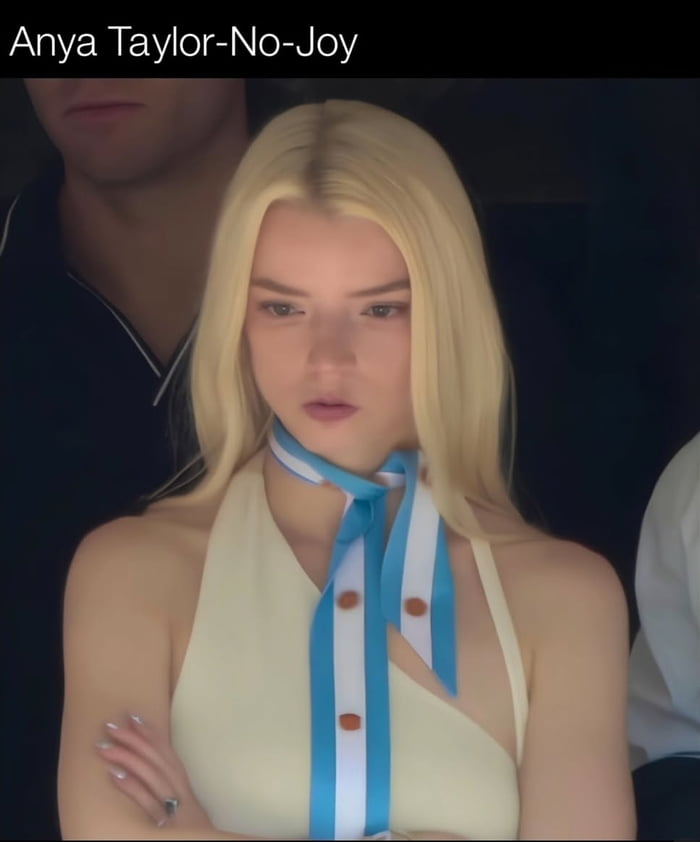 Anya Taylor-No-Joy. Anya Taylor-Joy with a serious or displeased expression, wearing a light top and a blue and white striped scarf.