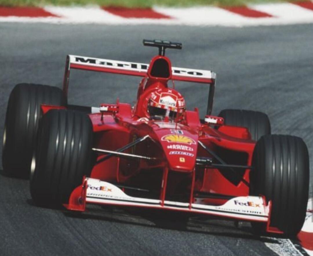 Red Formula 1 race car on a race track with slick tires, front wing details visible.