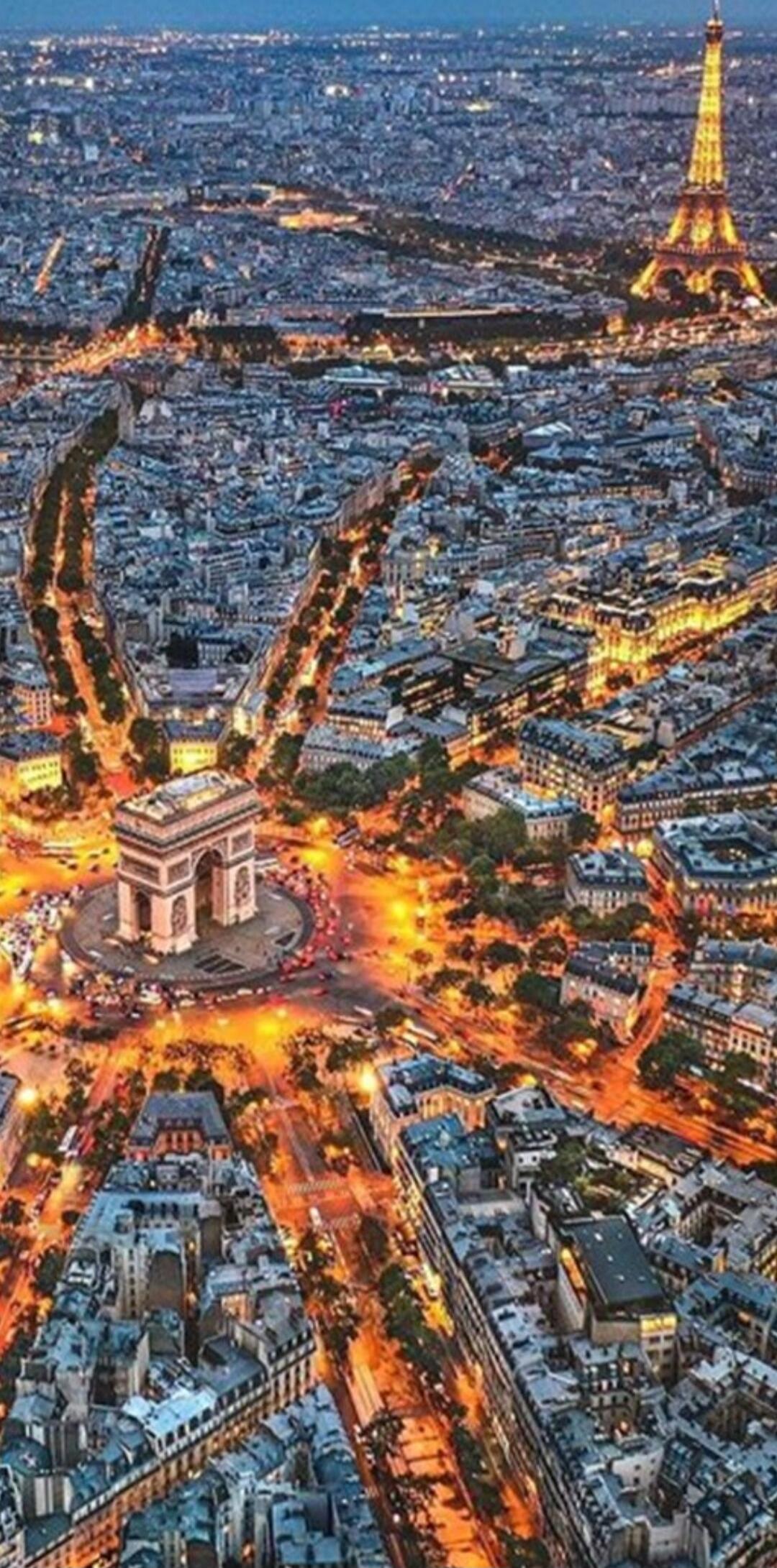 Paris at night featuring the Arc de Triomphe and illuminated avenues.