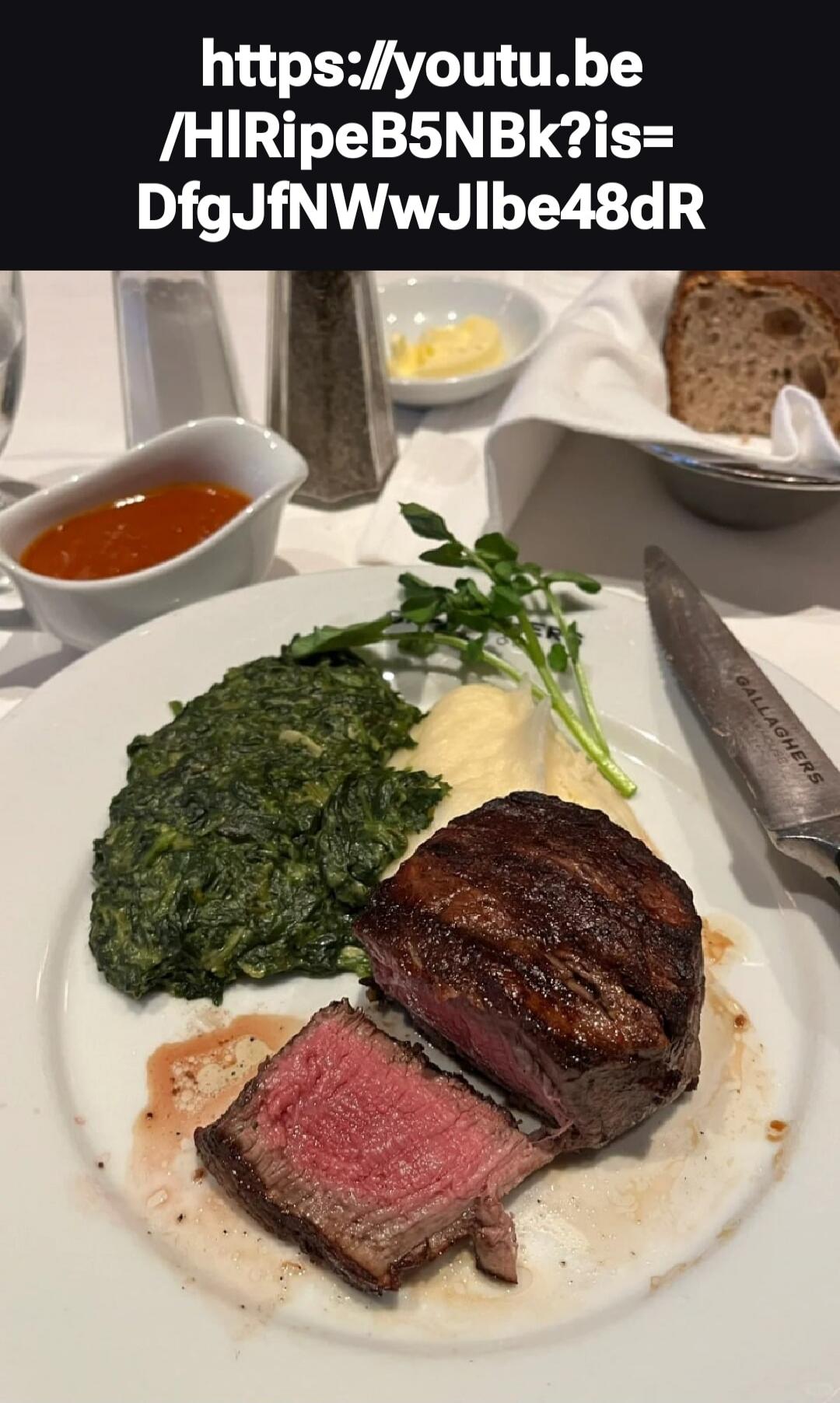 https://youtu.be/HIRipeB5NBk?is=DfgJfNWWJlbe48dR GALLAGHERS A plate with a medium-rare steak, creamed spinach, mashed potatoes, and a side sauce. Bread and butter are in the background.
