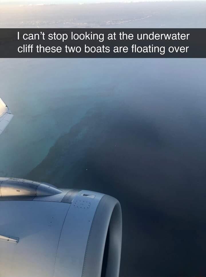 cant stop looking at the underwater cliff these two boats are floating over