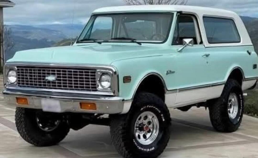 Vintage 1970s Chevrolet pickup truck in mint green and white two-tone color, lifted with large tires.