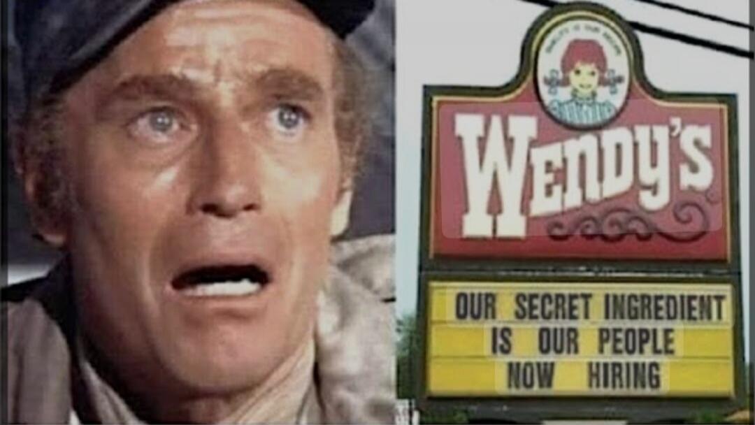 OUR SECRET INGREDIENT IS OUR PEOPLE NOW HIRING. A man with a shocked expression, referencing the movie 'Soylent Green', is juxtaposed with a Wendy's sign that reads 'Our secret ingredient is our people. Now hiring.'
