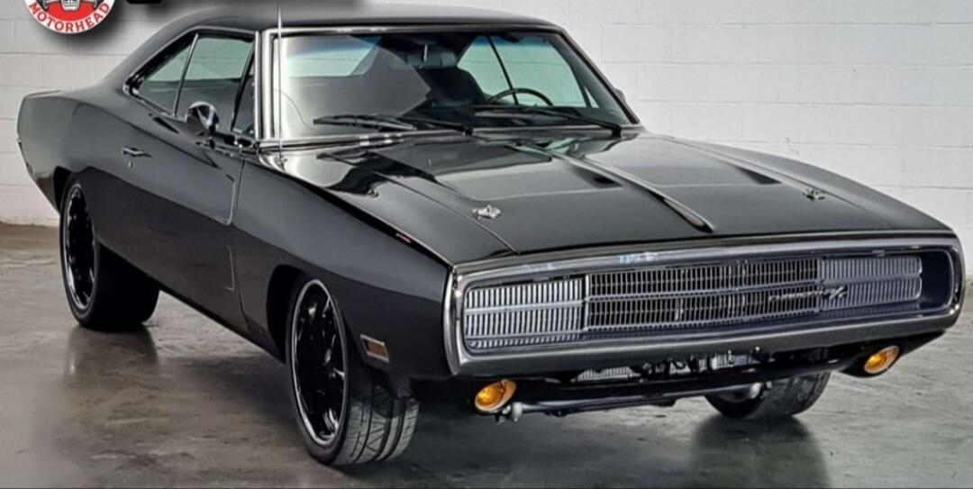 A dark gray vintage muscle car photographed indoors.