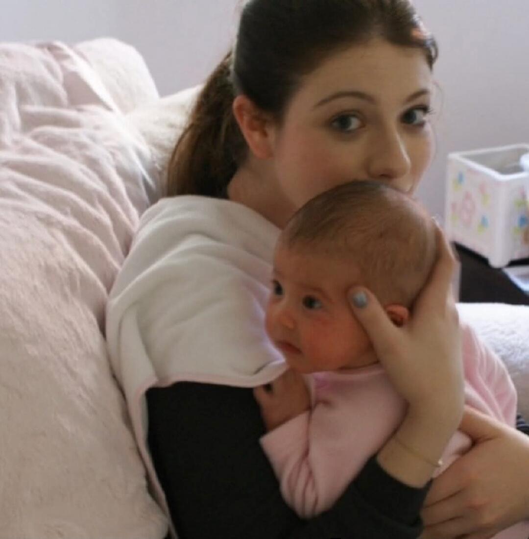 A woman holding a baby on a couch.