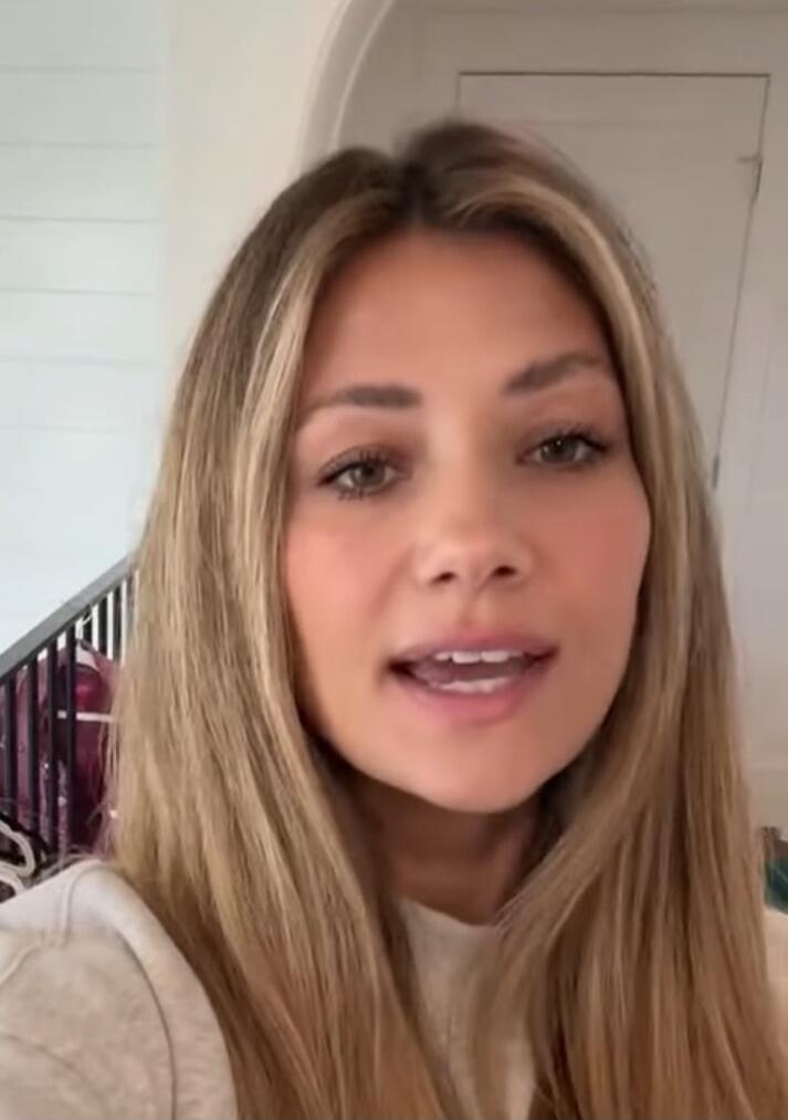 A woman with long blonde hair is looking directly at the camera and appears to be speaking.