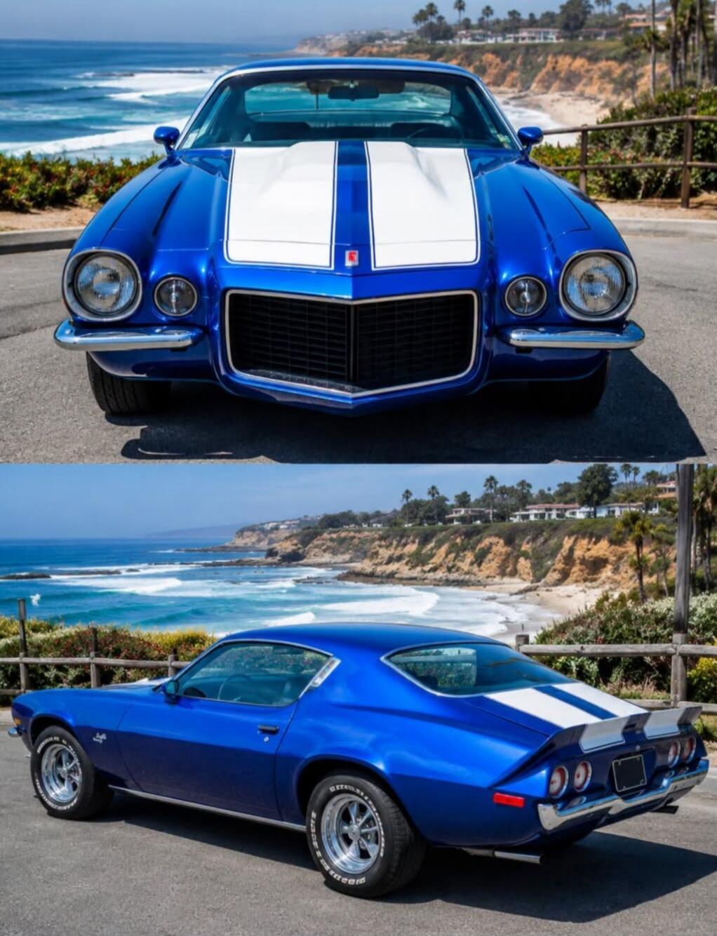 A classic blue Chevrolet Camaro with white racing stripes is parked on a road overlooking a scenic ocean coastline. The car is shown from both front and rear angles, highlighting its vintage design against a beautiful natural backdrop with waves crashing on the shore and palm trees in the distance.
