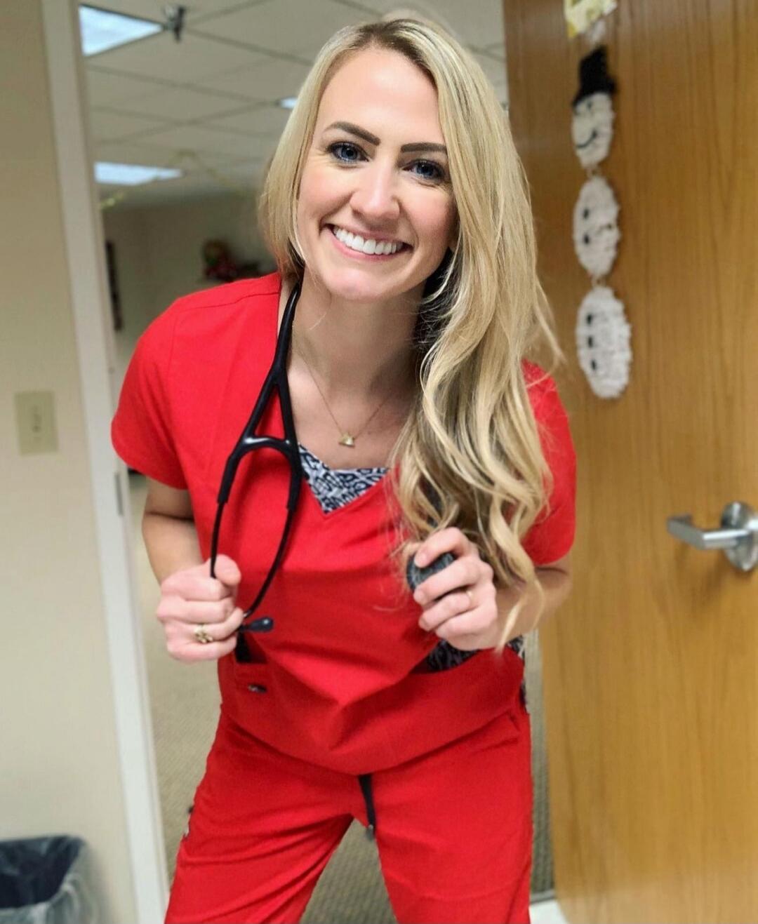 Smiling woman in red scrubs holding a stethoscope.