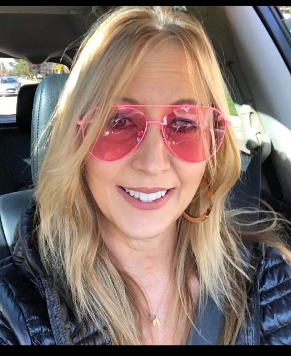 Photo of a smiling woman wearing pink sunglasses in a car.