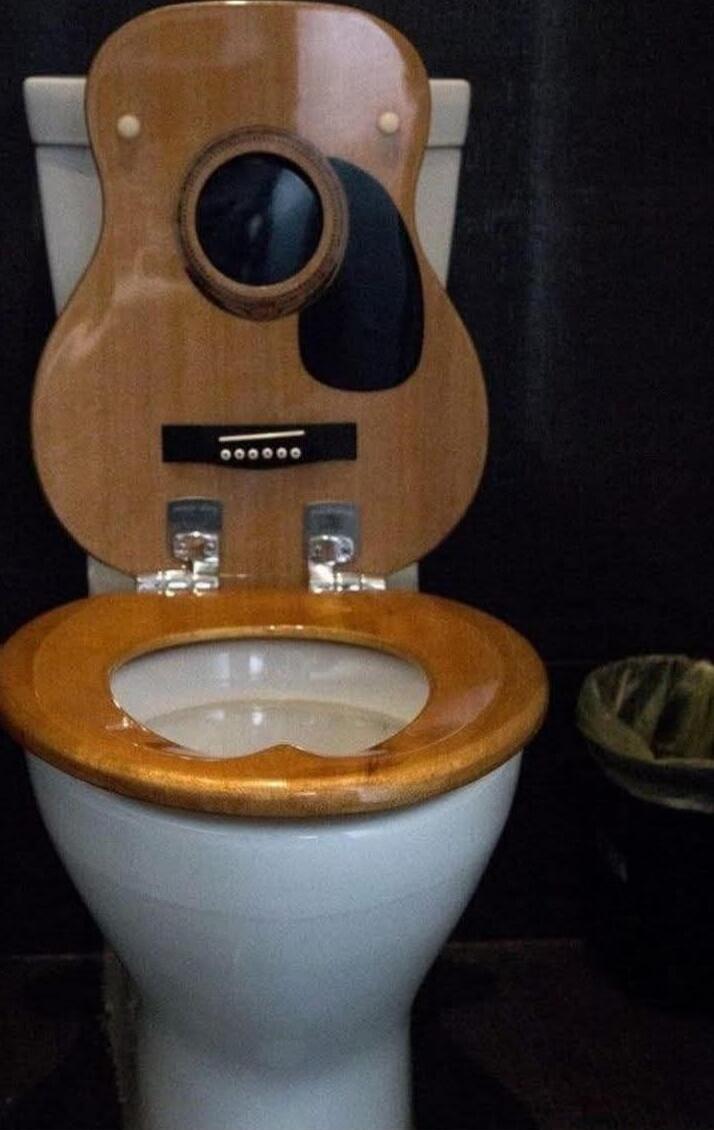 A toilet with a wooden guitar body used as the tank and lid.