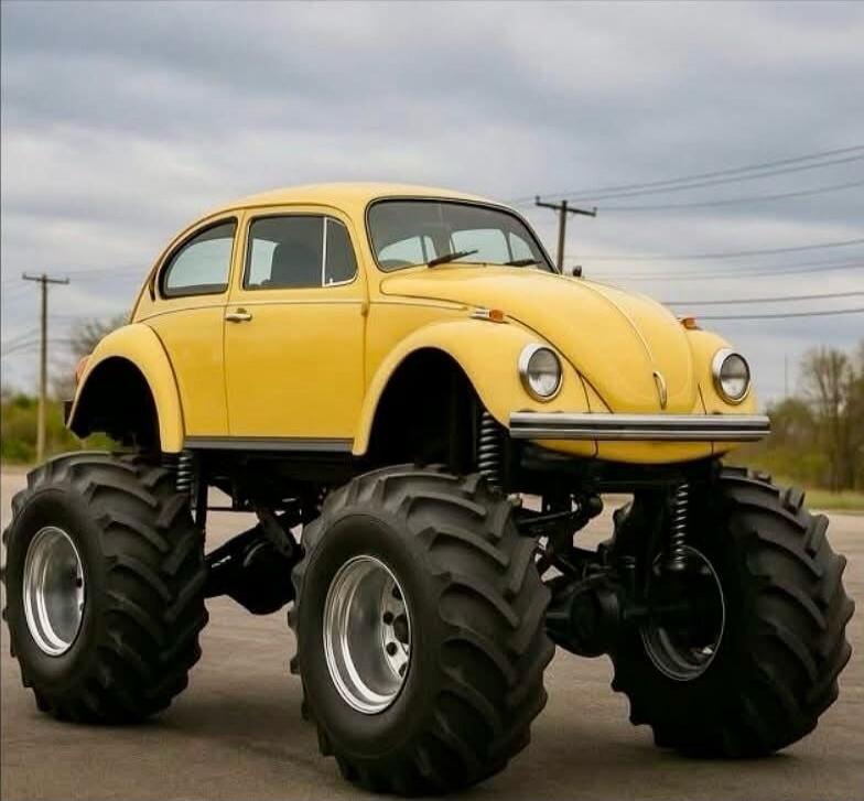 A yellow vintage Volkswagen Beetle converted into a monster truck with oversized tires.