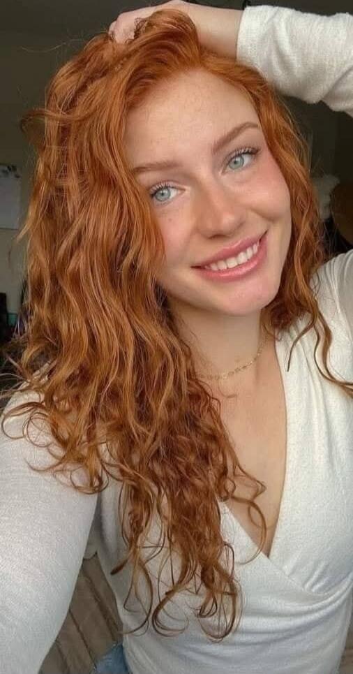 A smiling woman with wavy red hair.