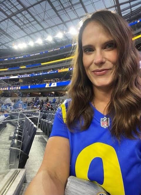 Person wearing blue NFL jersey with number 0 at a stadium.