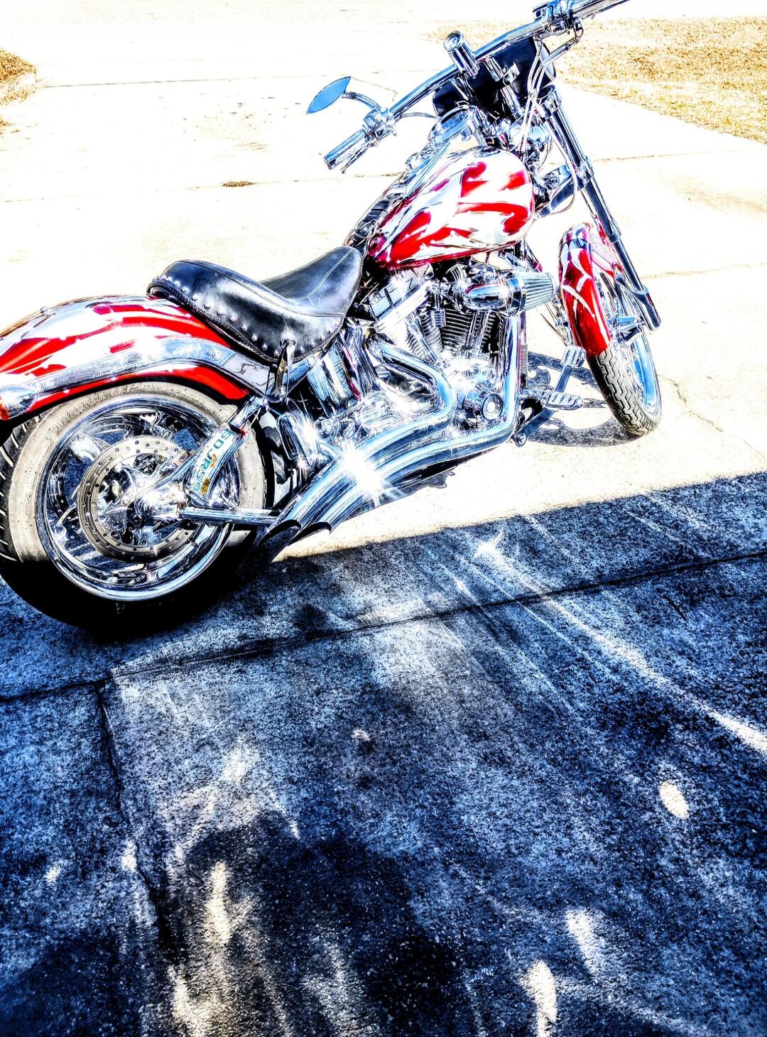 A red and white custom motorcycle parked on a paved surface.