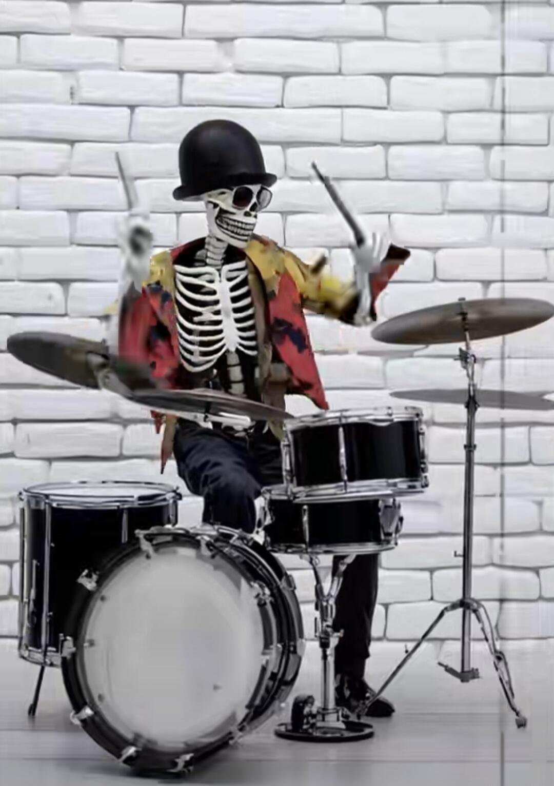Skeleton wearing a black bowler hat and colorful vest, playing a drum set in front of a white brick wall.