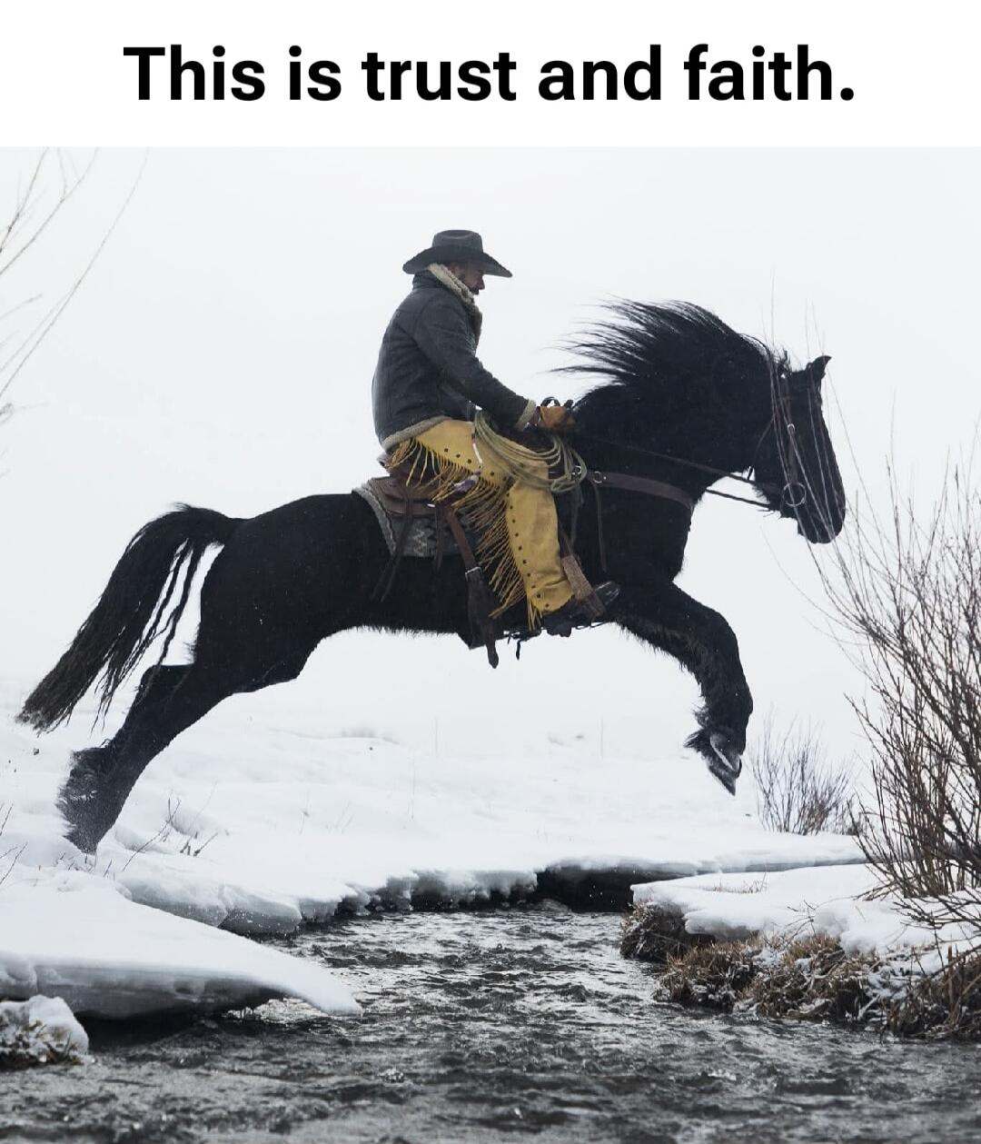 This is trust and faith. A cowboy on a black horse is captured mid-air, jumping over a small stream in a snowy, winter landscape.