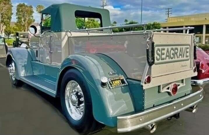 A vintage custom pickup truck is parked outdoors. The tailgate has 'SEAGRAVE' written on it. The license plate reads 'SAMMY'.