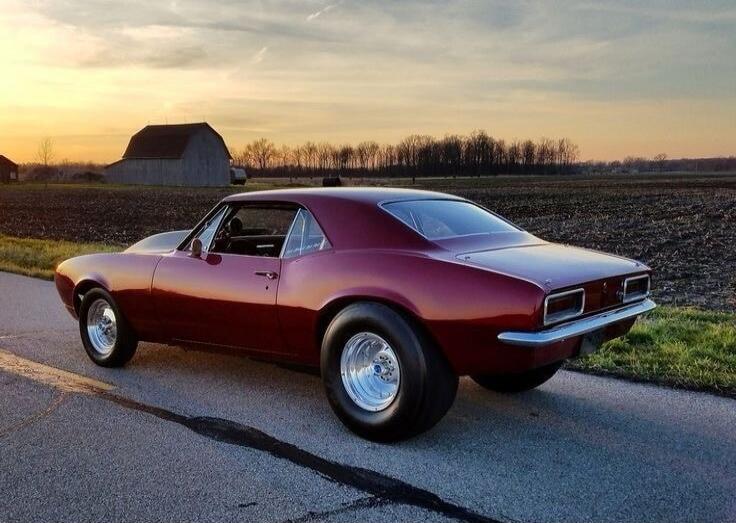 Purple vintage car on a rural road at sunset.