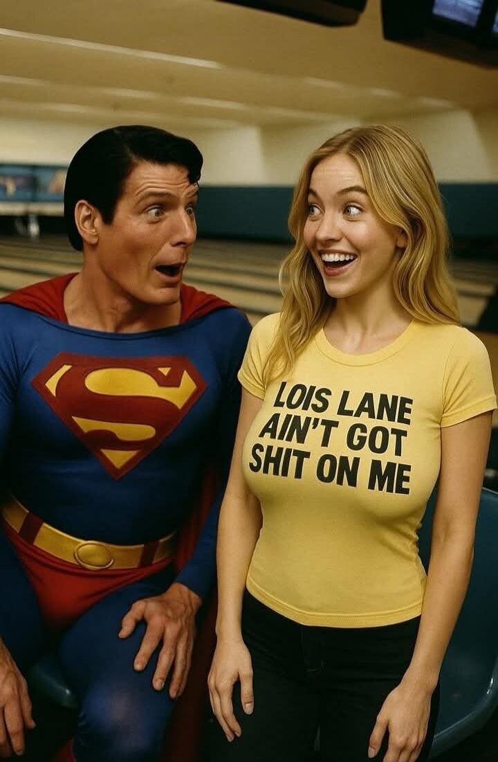 A man dressed as Superman looks surprised at a smiling woman wearing a yellow t-shirt that reads 'LOIS LANE AIN'T GOT SHIT ON ME'.