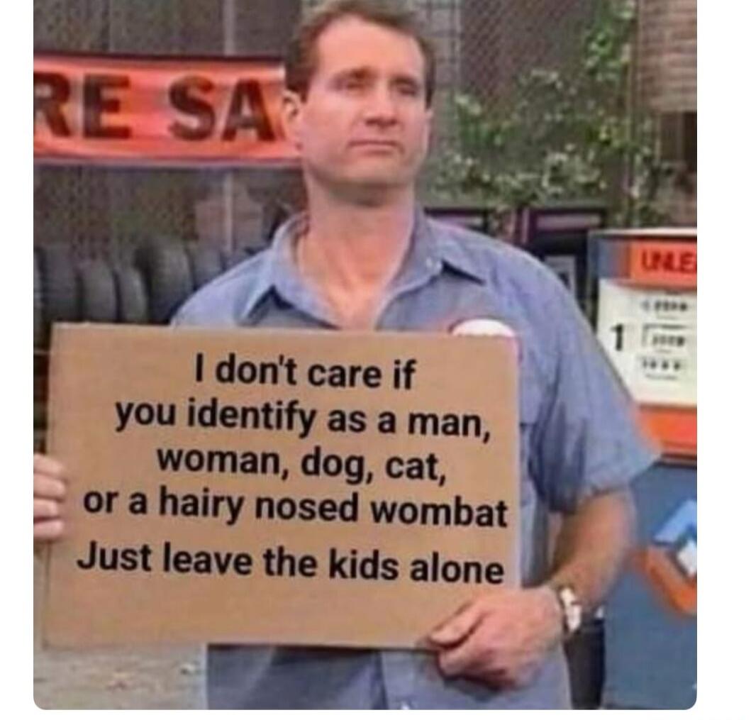 I don't care if you identify as a man, woman, dog, cat, or a hairy nosed wombat Just leave the kids alone. Al Bundy holding a sign.