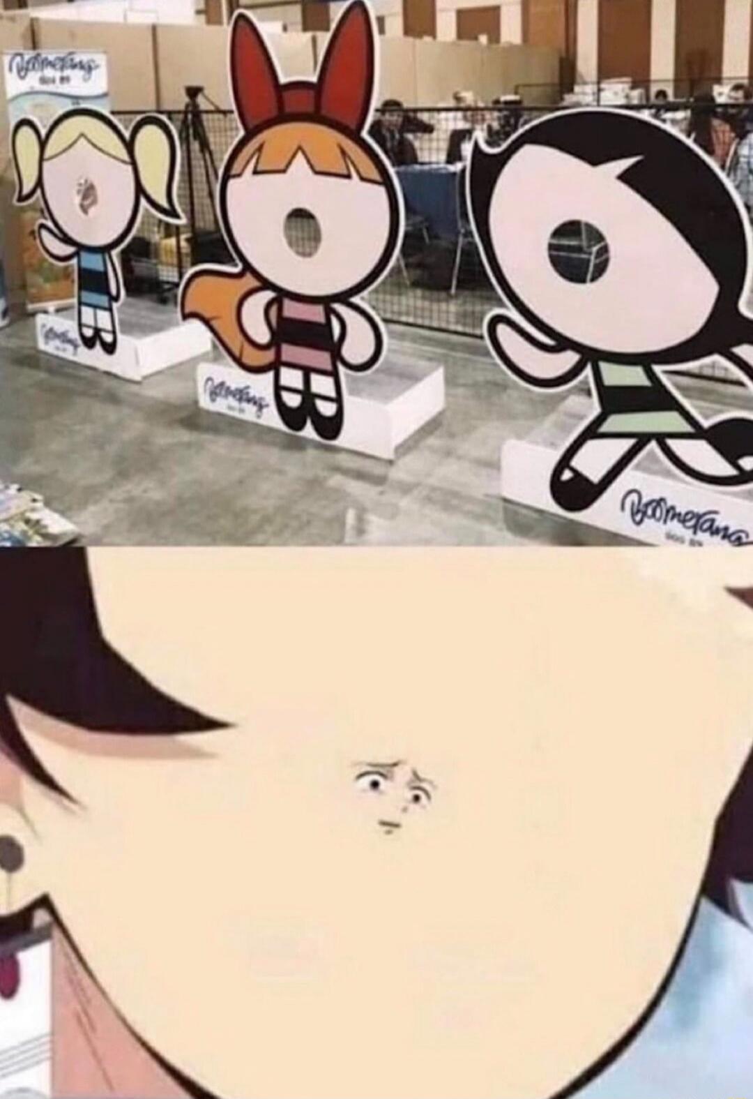 Three cartoon standees of the Powerpuff Girls are on display at an event, with a close-up shot revealing a small human face on a surface in the foreground.