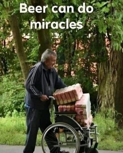 Beer can do miracles. An elderly man is pushing a wheelchair heavily loaded with cases of beer, walking alongside it.