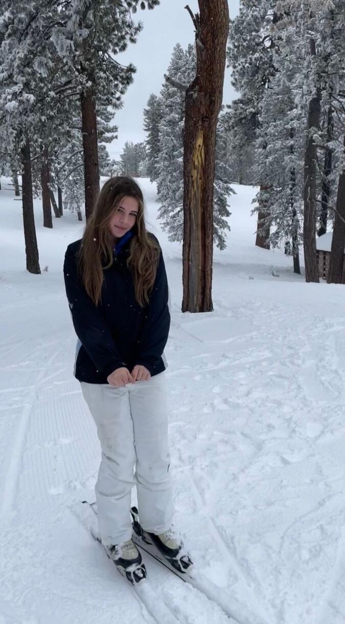 A person wearing winter clothes standing on skis in a snowy forest.