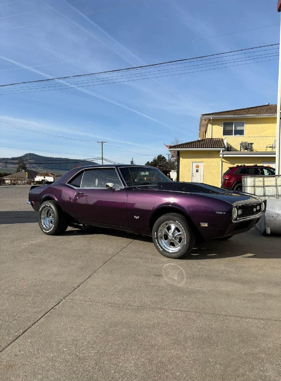 A classic purple Chevrolet Camaro SS with a 327 engine, featuring BFGoodrich Radial T/A tires, parked on a sunny day.