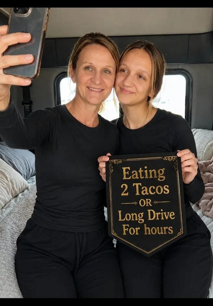 Two women taking a selfie. One woman holds a sign that reads: 