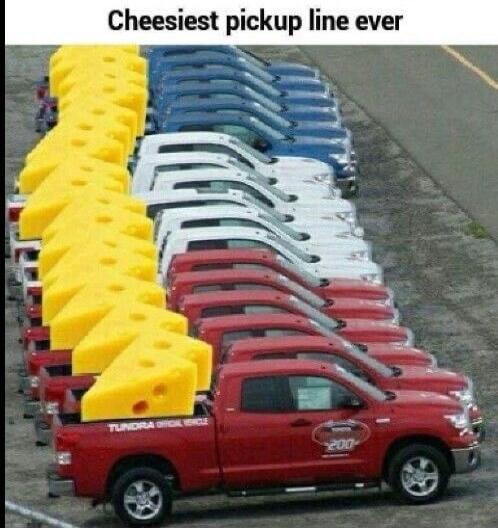 Cheesiest pickup line ever. A long line of red pickup trucks, each carrying a giant wedge of cheese, creating a visual pun on the phrase 'pickup line'.