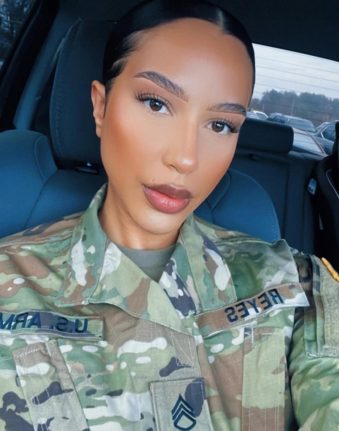 A woman in a US Army uniform, identified by the name 'REYES' and rank of Staff Sergeant, is taking a selfie in a car. The uniform also shows 'U.S. ARMY'.