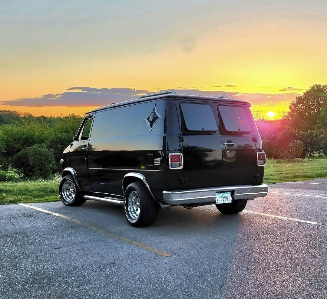 A black van parked in a parking lot at sunset.