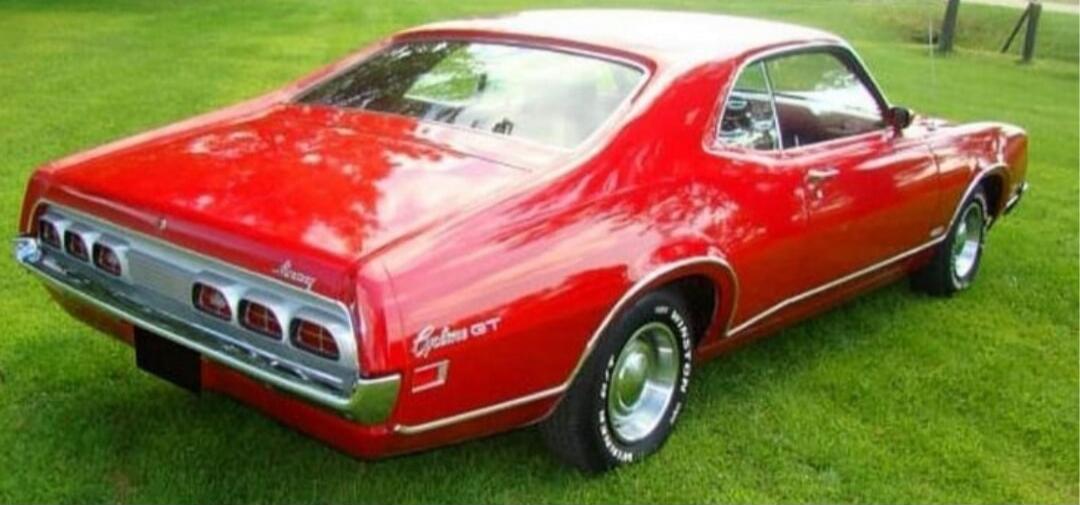 Rear view of a red classic muscle car parked on grass