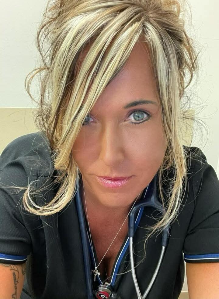 Woman in medical scrubs with a stethoscope around her neck.