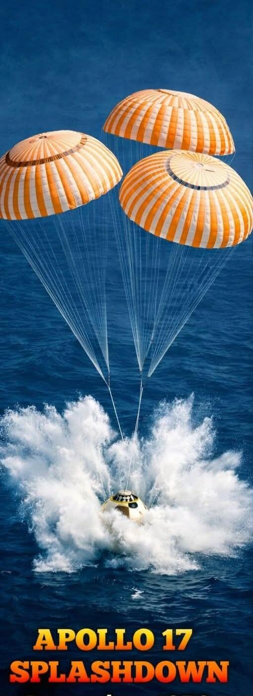 APOLLO 17 SPLASHDOWN. The Apollo 17 command module splashes down in the ocean, guided by three large orange and white parachutes, creating a significant splash.