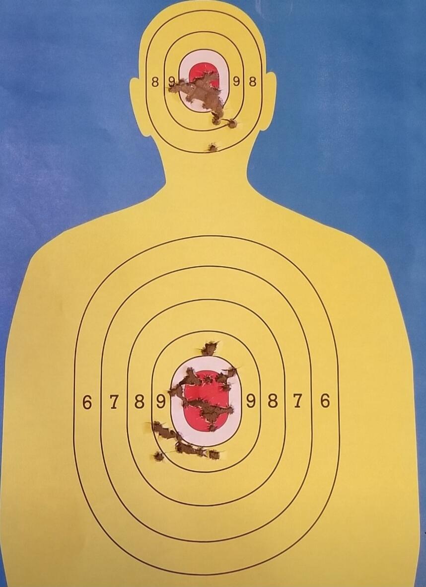 Target silhouette with bullet holes in head and torso; concentric rings with numbers near the rings.