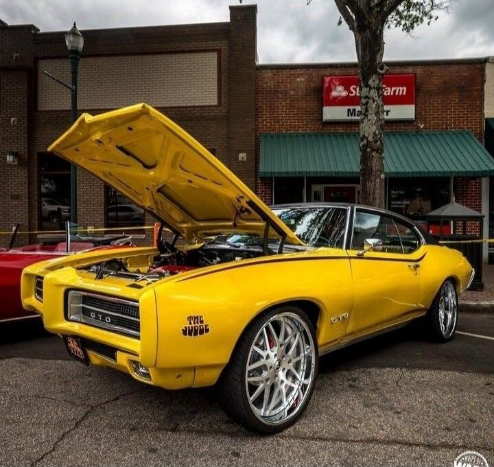 Yellow classic muscle car with hood open.