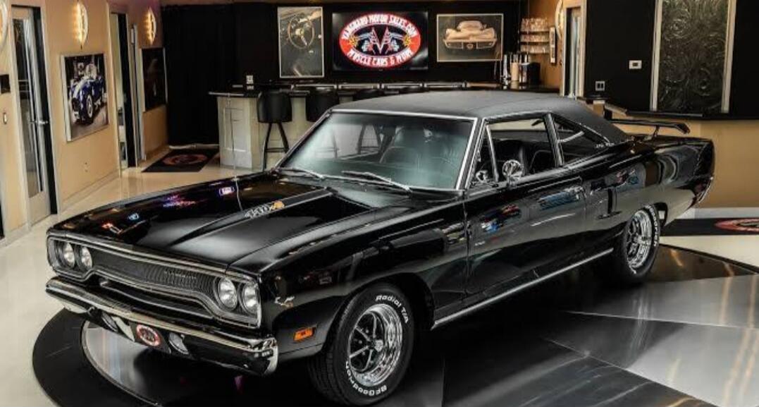 Black classic muscle car on a showroom floor.