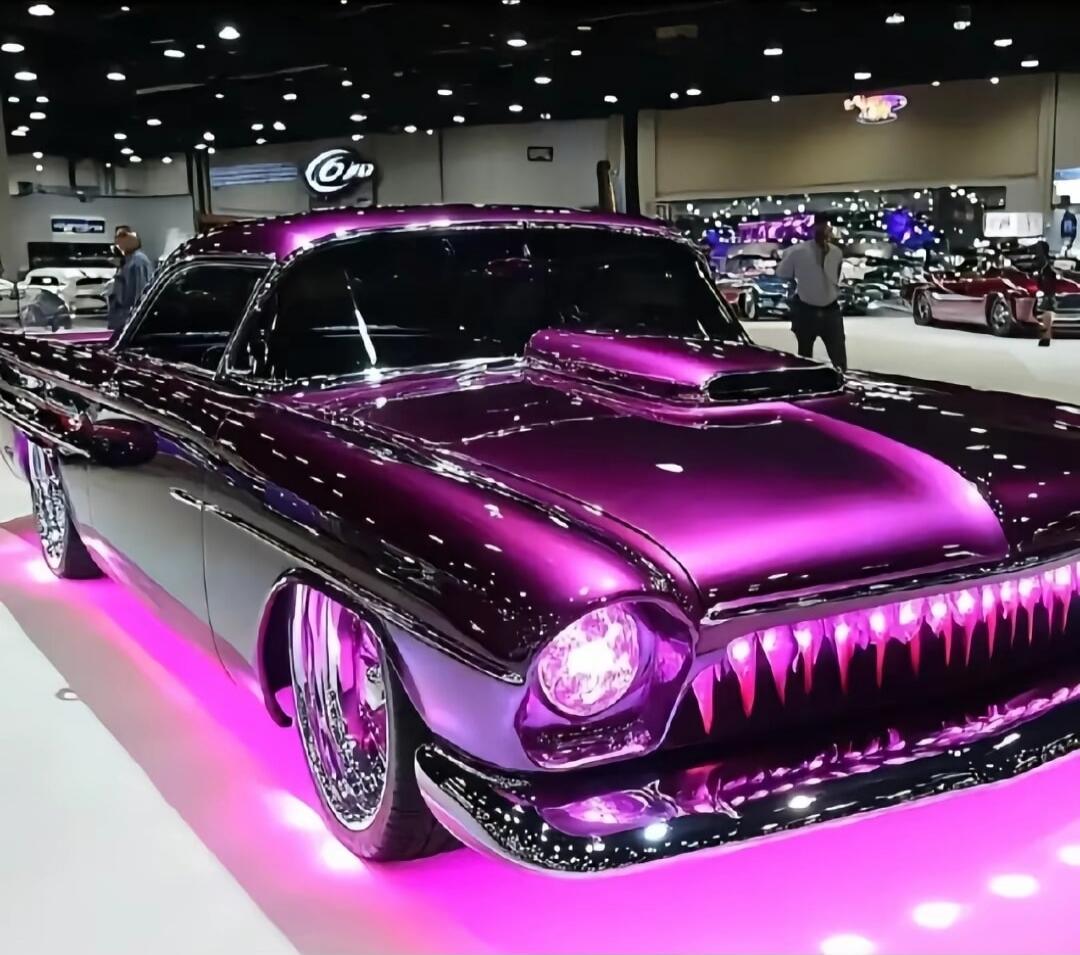 Purple classic car with shiny chrome, purple lighting at an auto show.