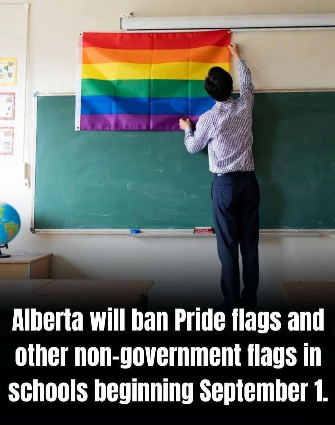Alberta will ban Pride flags and other non-government flags in schools beginning September 1. A person is hanging a rainbow Pride flag on a chalkboard in a classroom.