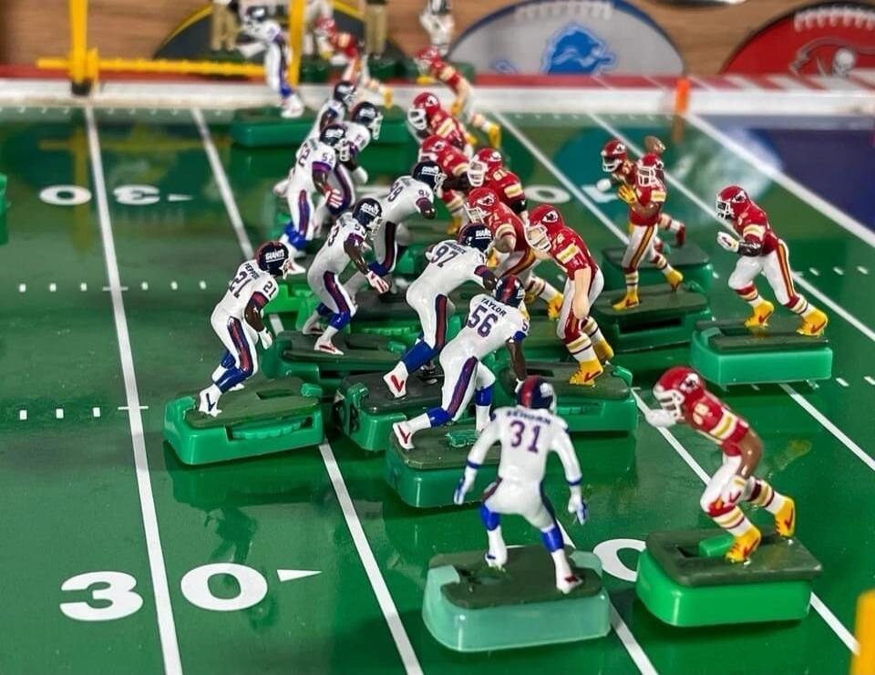 Tabletop miniature American football game with players lined up on a green field.