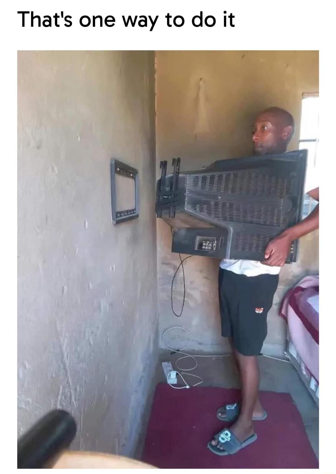 That's one way to do it. A man is attempting to mount an old, bulky CRT television onto a modern, flat-screen TV wall mount.