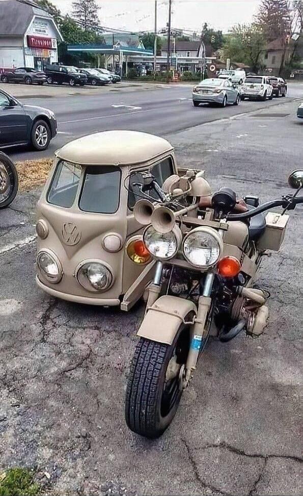 A unique custom motorcycle with a sidecar designed to resemble the front of a classic Volkswagen Type 2 van, parked on a street.