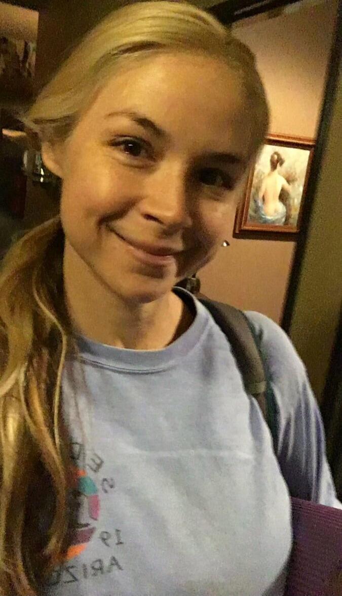 A young woman smiling at the camera indoors.