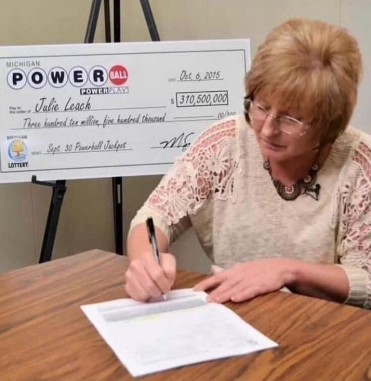 MICHIGAN POWERBALL POWERPLAY Oct 6, 2015 Pay to the order of Julie Leach $310,500,000 Three hundred ten million, five hundred thousand Sept 30 Powerball Jackpot LOTTERY. A woman is signing documents, likely related to her lottery winnings.