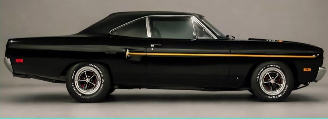 A classic black muscle car with a yellow stripe on its side, parked against a plain background.